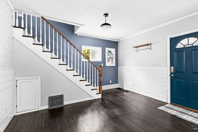 Entrance foyer featuring crown molding and dark ha