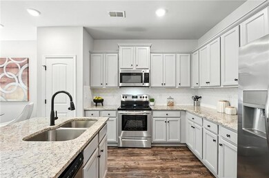 Kitchen with stainless steel appliances, backsplash, dark wood-style flooring, light stone countertops, and recessed lighting