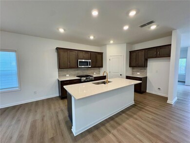 Kitchen featuring appliances with stainless steel finishes, dark brown cabinetry, decorative backsplash, wood finished floors, and recessed lighting