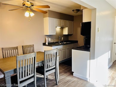 Kitchen featuring dark countertops, light wood-type flooring, white cabinets, and a ceiling fan