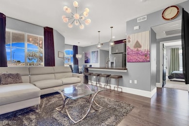 Living area featuring baseboards, a notable chandelier, visible vents, and wood finished floors