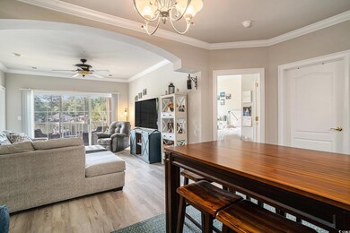 Living room featuring arched walkways, a chandelier, light wood finished floors, a ceiling fan, and crown molding