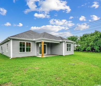 Rear view of property featuring a patio, a yard, and a shingled roof