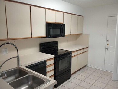 Kitchen with white cabinetry, black appliances, si