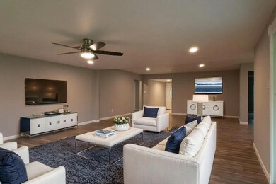 (Virtually Staged) Spacious living room with comfortable couches, a sleek TV, and modern design elements like a coffee table and elegant decor.
