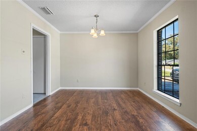Unfurnished dining area featuring ornamental molding, a textured ceiling, wood finished floors, and a chandelier