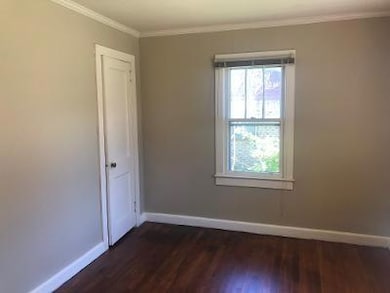 Spare room with baseboards, dark wood-type flooring, and crown molding