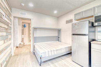 Bedroom featuring freestanding refrigerator, light wood-style flooring, and recessed lighting