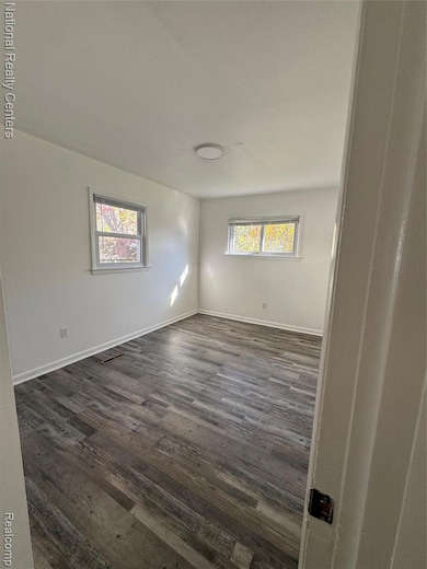 Unfurnished room with dark wood finished floors and baseboards
