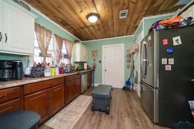 Kitchen featuring appliances with stainless steel finishes, wooden ceiling, white cabinets, light wood-type flooring, and brown cabinetry