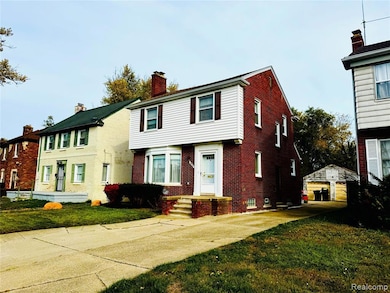 Colonial inspired home featuring an outdoor structure, brick siding, a front lawn, and a detached garage