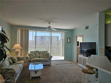 Carpeted living area featuring a ceiling fan, visi