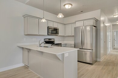 Kitchen with stainless steel appliances, a peninsula, decorative light fixtures, light wood-type flooring, and a breakfast bar