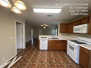 Kitchen with white appliances, light countertops, a peninsula, brown cabinets, and ceiling fan