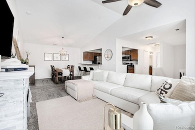 Living room featuring vaulted ceiling, a chandelier, and ceiling fan