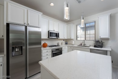 Kitchen featuring appliances with stainless steel finishes, decorative light fixtures, recessed lighting, white cabinetry, and a center island