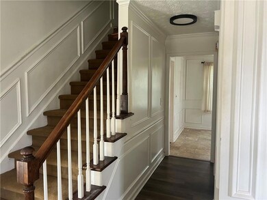 Stairway featuring a decorative wall, a textured ceiling, ornamental molding, and wood finished floors