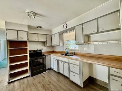 Kitchen featuring open shelves, dark wood-style flooring, stainless steel electric range oven, light countertops, and white cabinetry