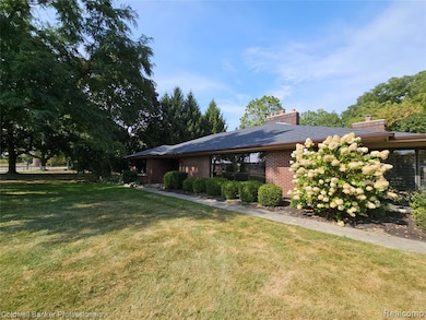 View of front of home with brick siding, a front yard, and a chimney