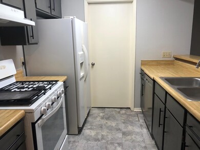 Kitchen with white gas stove, light countertops, under cabinet range hood, and gray cabinetry