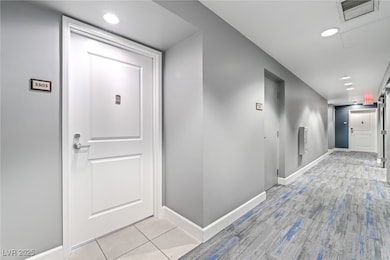 Hallway with baseboards, recessed lighting, and li