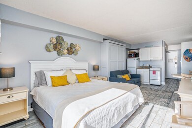 Bedroom featuring wood finish floors, freestanding refrigerator, and a closet