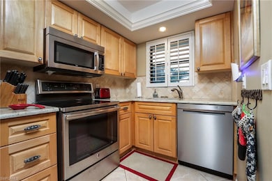 Kitchen featuring appliances with stainless steel finishes, backsplash, light stone counters, recessed lighting, and light tile patterned flooring