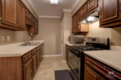 Kitchen with ornamental molding, stainless steel appliances, dark brown cabinets, sink, and light tile floors