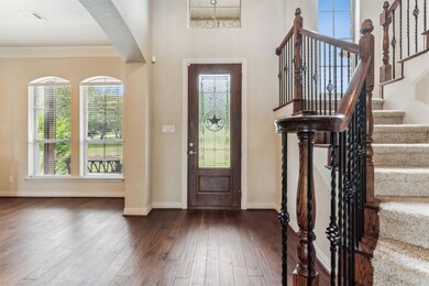 Entrance foyer with dark hardwood / wood-style floors, ornamental molding, and a towering ceiling