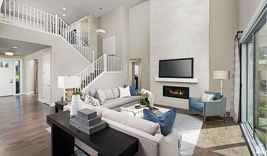 Living area with a towering ceiling, dark wood-type flooring, a fireplace, stairway, and recessed lighting