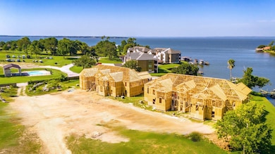 New lakefront homes in construction with wood framing, offering beautiful water views. Nearby amenities include a pool and lush green spaces, ideal for serene living.