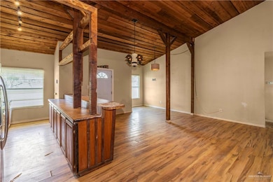 Kitchen featuring pendant lighting, vaulted ceiling, light wood finished floors, open floor plan, and wood ceiling