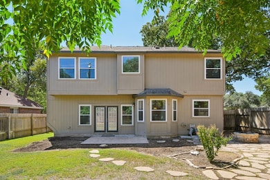Rear view of house featuring a patio, a fenced backyard, a shingled roof, french doors, and an outdoor fire pit