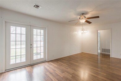 Light-filled den with ceiling fan and doors to bac