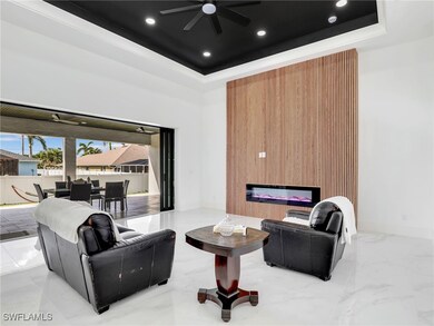 Living area featuring a tray ceiling, a glass covered fireplace, recessed lighting, and marble finish floors