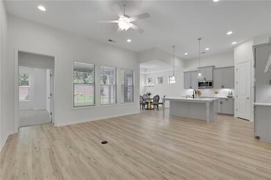 Living area with light wood-style flooring, a ceiling fan, and recessed lighting