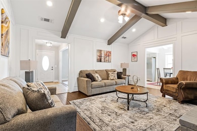 Living room with visible vents, a decorative wall,