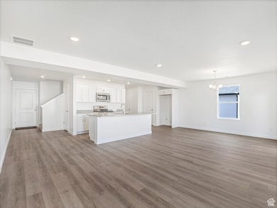 Unfurnished living room featuring light wood-style flooring, recessed lighting, and a chandelier