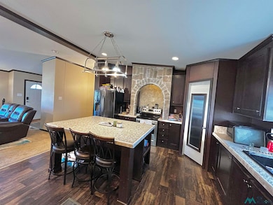 Kitchen featuring a breakfast bar, stainless steel appliances, dark wood-type flooring, dark brown cabinets, and a kitchen island