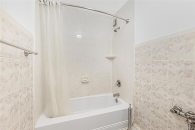 Bathroom featuring shower / tub combo and tile walls