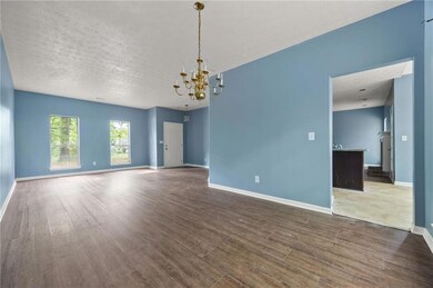 Unfurnished room featuring wood finished floors, a chandelier, baseboards, and a textured ceiling