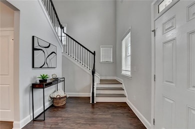 Foyer featuring stairs, dark wood-type flooring, and a high ceiling