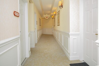 Hallway featuring light colored carpet
