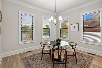 Sunlit filled Dining room with chandelier, Luxury Vinyl Plank flooring and crown molding.
