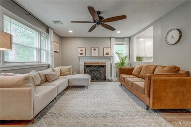 Living room featuring light hardwood / wood-style floors, a textured ceiling, a fireplace, and ceiling fan