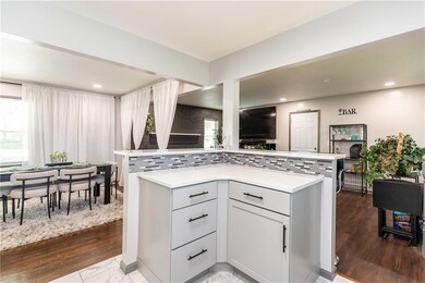 Kitchen featuring backsplash, white cabinets, hardwood / wood-style flooring, and kitchen peninsula