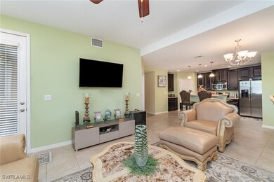 Living area with light tile patterned flooring, a chandelier, ceiling fan, and baseboards