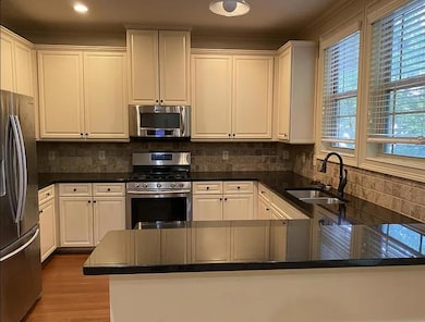 Kitchen featuring appliances with stainless steel finishes, white cabinets, and crown molding