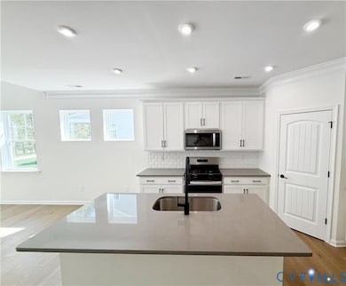Stepping inside, you’ll travel through the inviting foyer to the kitchen which features a center island, quartz countertops, gas cooking, and a walk-in pantry. 
