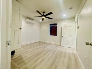 Unfurnished bedroom featuring light wood-style floors, a ceiling fan, recessed lighting, and a wall unit AC
